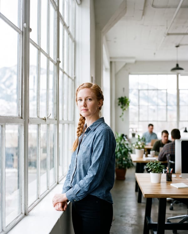 Jess Thornley, payroll lead, standing by a tall window in the Sugar House studio